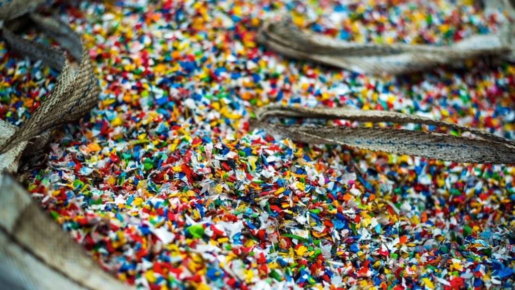 bioaqualife: A close-up view of colorful plastic confetti or shredded plastic pieces inside a large woven sack with visible handles.